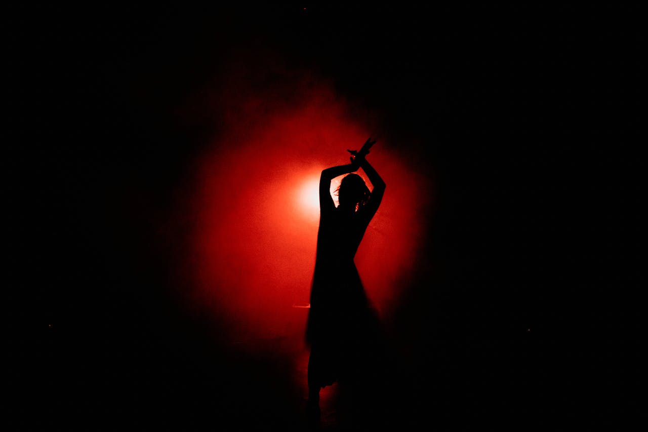 Captivating silhouette of a dancer performing gracefully with a dramatic red background.